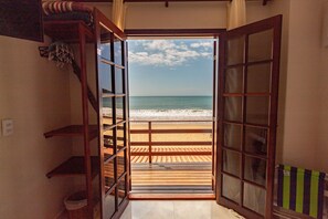 Una puerta abierta que da a una terraza de madera con vista a una playa.