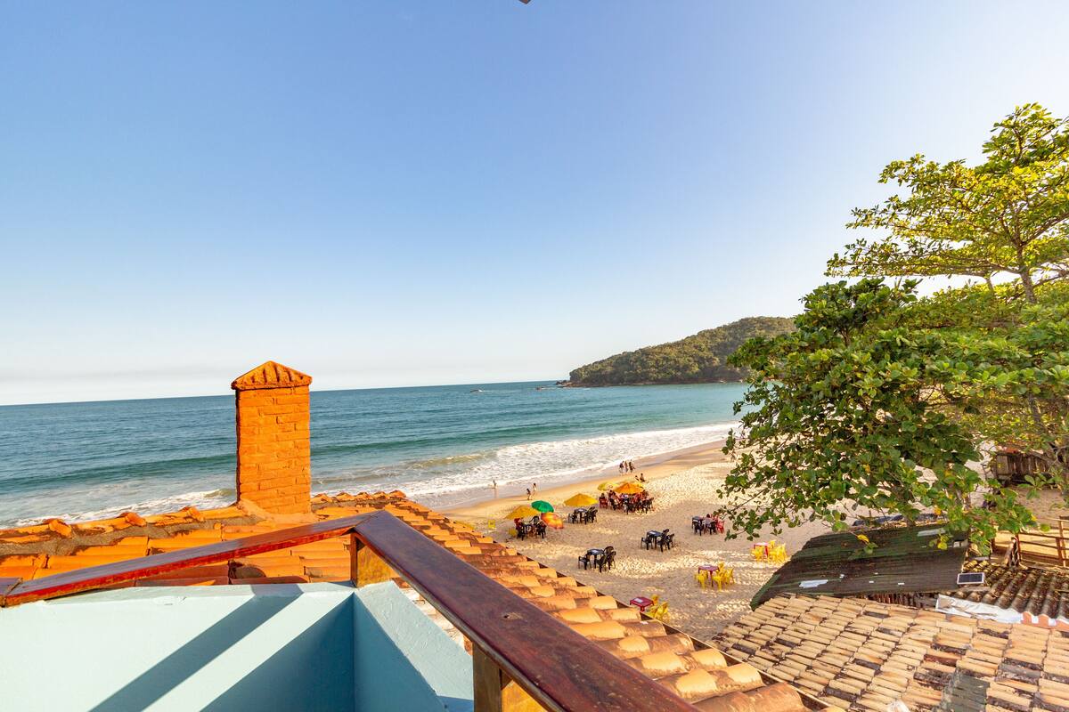Ein Strand mit einer Holzkonstruktion, Sonnenschirmen und Blick aufs Meer.