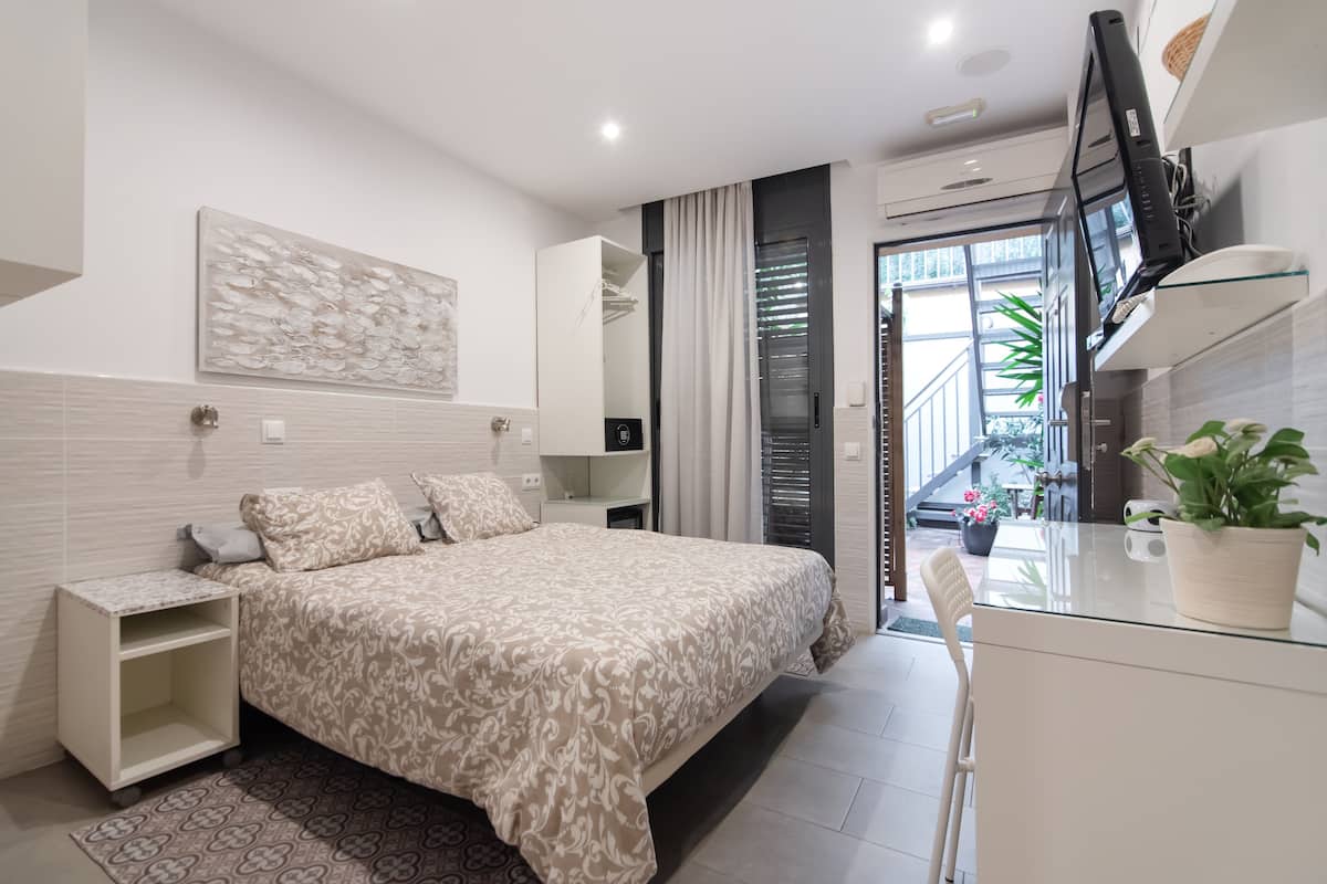 Um quarto moderno com uma cama grande, mesas de cabeceira, uma escrivaninha e um vaso de planta.
