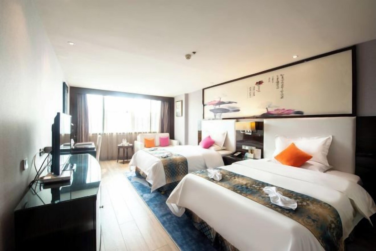 Una habitación de hotel con dos camas, un escritorio y un ventanal grande.