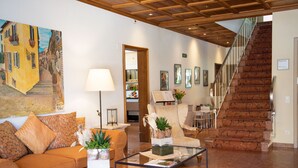 Un salon spacieux avec un plafond en bois, un canapé, une table basse et un escalier.
