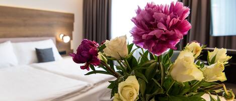 Una habitación de hotel con una cama, un florero y un televisor al fondo.
