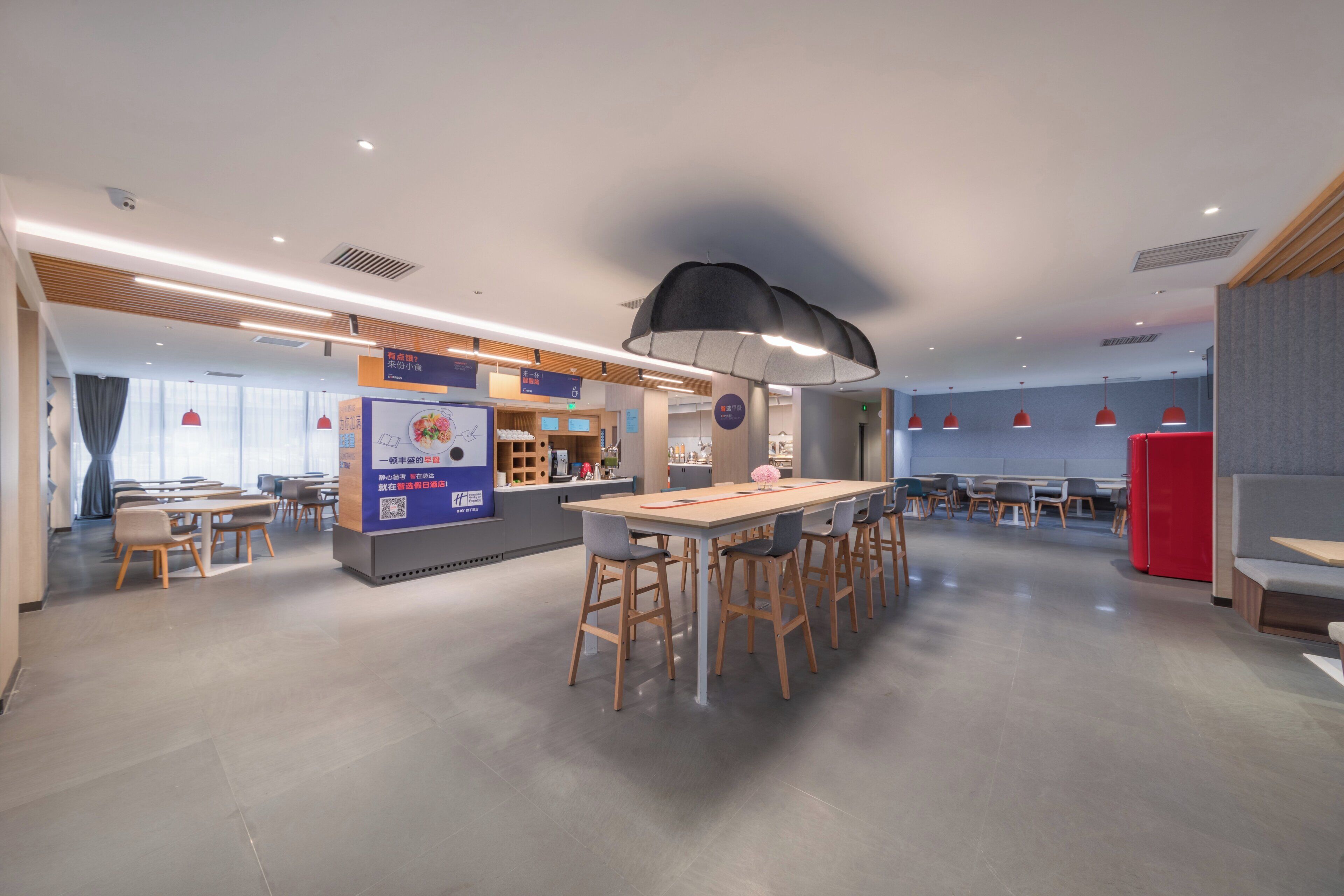 A modern dining area with a long table, bar stools, and a counter with a menu.