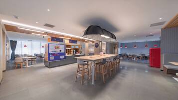 A modern dining area with a long table, bar stools, and a counter with a menu.