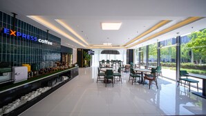 A modern coffee shop with a bar area, seating, and large windows offering a view of the outdoors. - Holiday Inn Express Beijing Shijingshan Lakeview by IHG (Beijing)