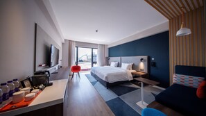 Una habitación de hotel moderna con cama, escritorio, silla y televisor.