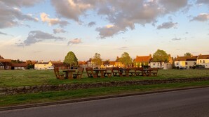 A grassy field with picnic tables and a stone wall. - Characterful Home In Vibrant Village! (Scorton)