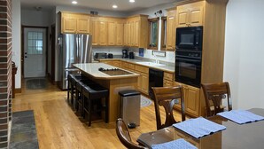 A modern kitchen with wooden cabinets, stainless steel appliances, and a central island with bar stools. - Spacious Lakefront Home, Amazing View, Great Dock, Sleeps 18 comfortably-Private (Bracey)