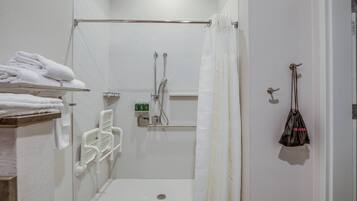Un baño moderno con cabina de ducha, un perchero con toallas dobladas, un secamanos y una bolsa colgada.
