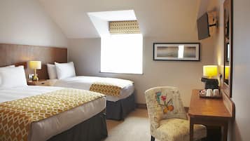Habitación de hotel con dos camas, un escritorio, una silla, un ventanal y un cuadro en la pared.
