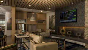 A modern lobby with a wooden ceiling, comfortable seating, a large TV displaying weather information, and decorative wall art. - Fairfield Inn & Suites by Marriott Louisville New Albany IN (New Albany)