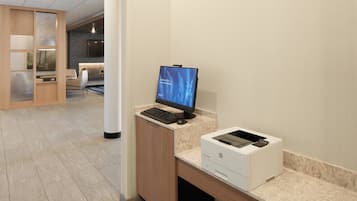 Een receptiebalie met een computer, printer en een zithoek op de achtergrond.