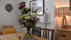 Et træspisebord med en vase blomster, en vævet dug og en vintage radio.