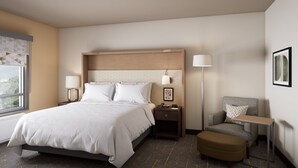 A hotel room with a bed, bedside tables, a chair, a desk, and a lamp. - Holiday Inn NW Houston Beltway 8 by IHG (Houston)