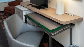 Une chambre d’hôtel équipée d’un bureau, d’une chaise, d’une télévision, d’une lampe et d’une poubelle.