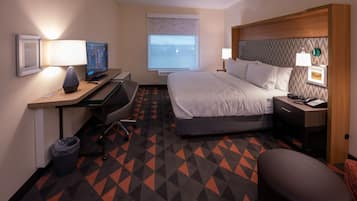 A hotel room with a bed, desk, chair, TV, and a window with a view.