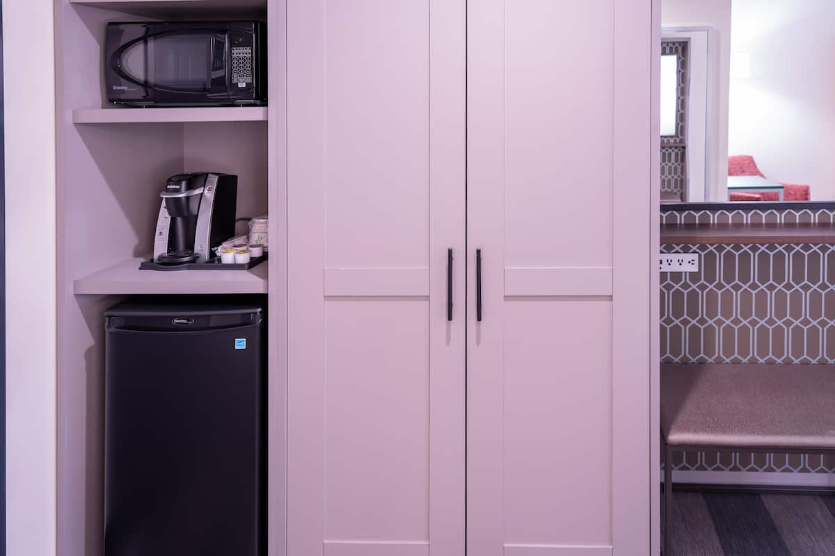 Una kitchenette equipada con microondas, cafetera y refrigerador.