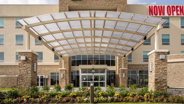 A Holiday Inn hotel entrance with a covered walkway, stone facade, and a 'NOW OPEN' sign. - Holiday Inn NW Houston Beltway 8 by IHG (Houston)