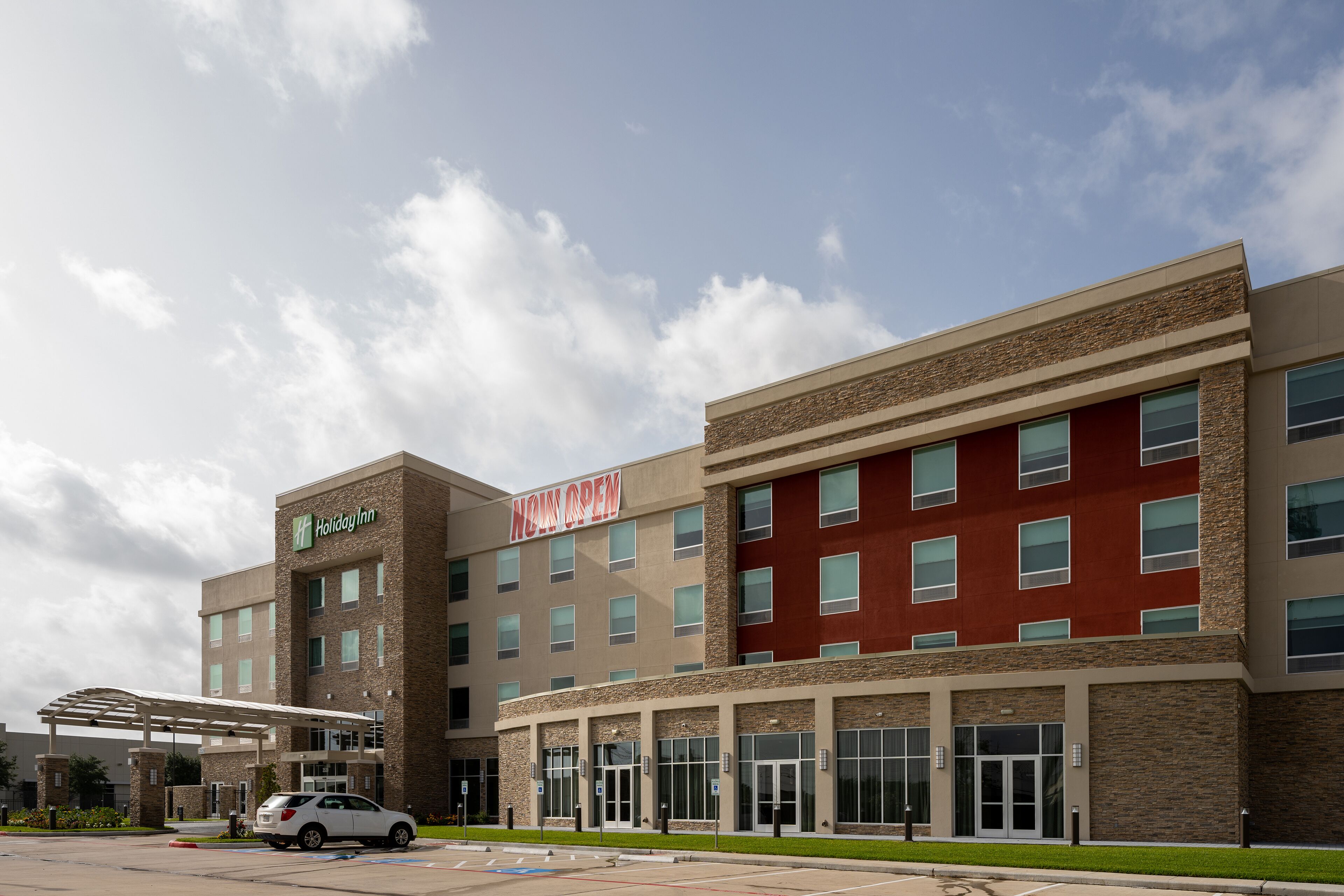 A Holiday Inn Express hotel with a modern design, featuring a mix of brick and red facade, large windows, and a covered entrance area.