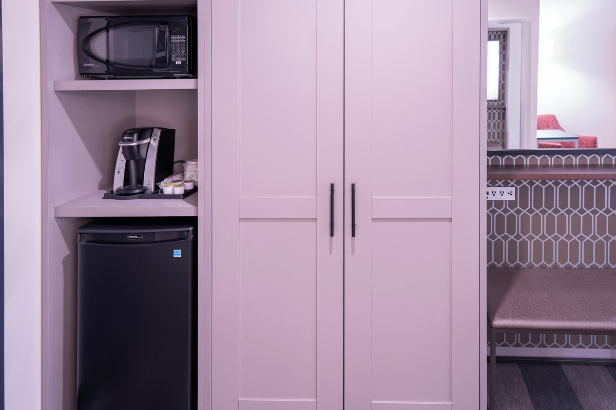 A kitchenette with a microwave, coffee maker, and refrigerator.