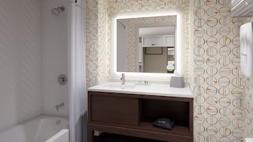 Un baño moderno con una bañera blanca, un tocador con espejo y papel tapiz estampado.