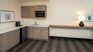 A compact kitchen with wooden cabinets, a built-in microwave, a sink, and a coffee maker. - Holiday Inn NW Houston Beltway 8 by IHG (Houston)