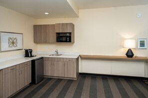 A compact kitchen with wooden cabinets, a built-in microwave, a sink, and a coffee maker. - Holiday Inn NW Houston Beltway 8 by IHG (Houston)