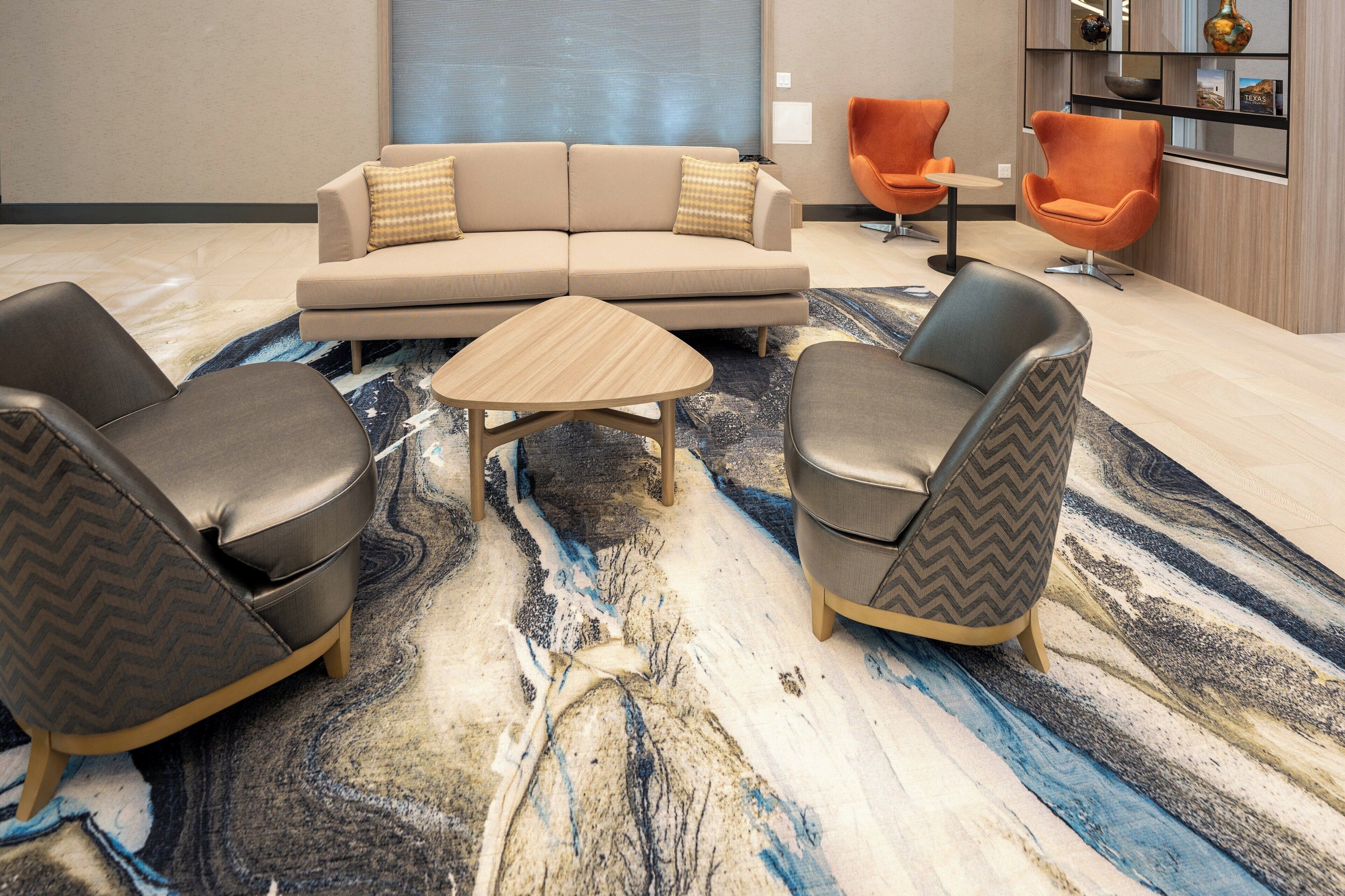 A modern living room with a sectional sofa, two armchairs, a coffee table, and a patterned rug.