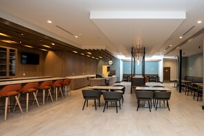 Een modern restaurant met een bar, hoge tafels en stoelen.