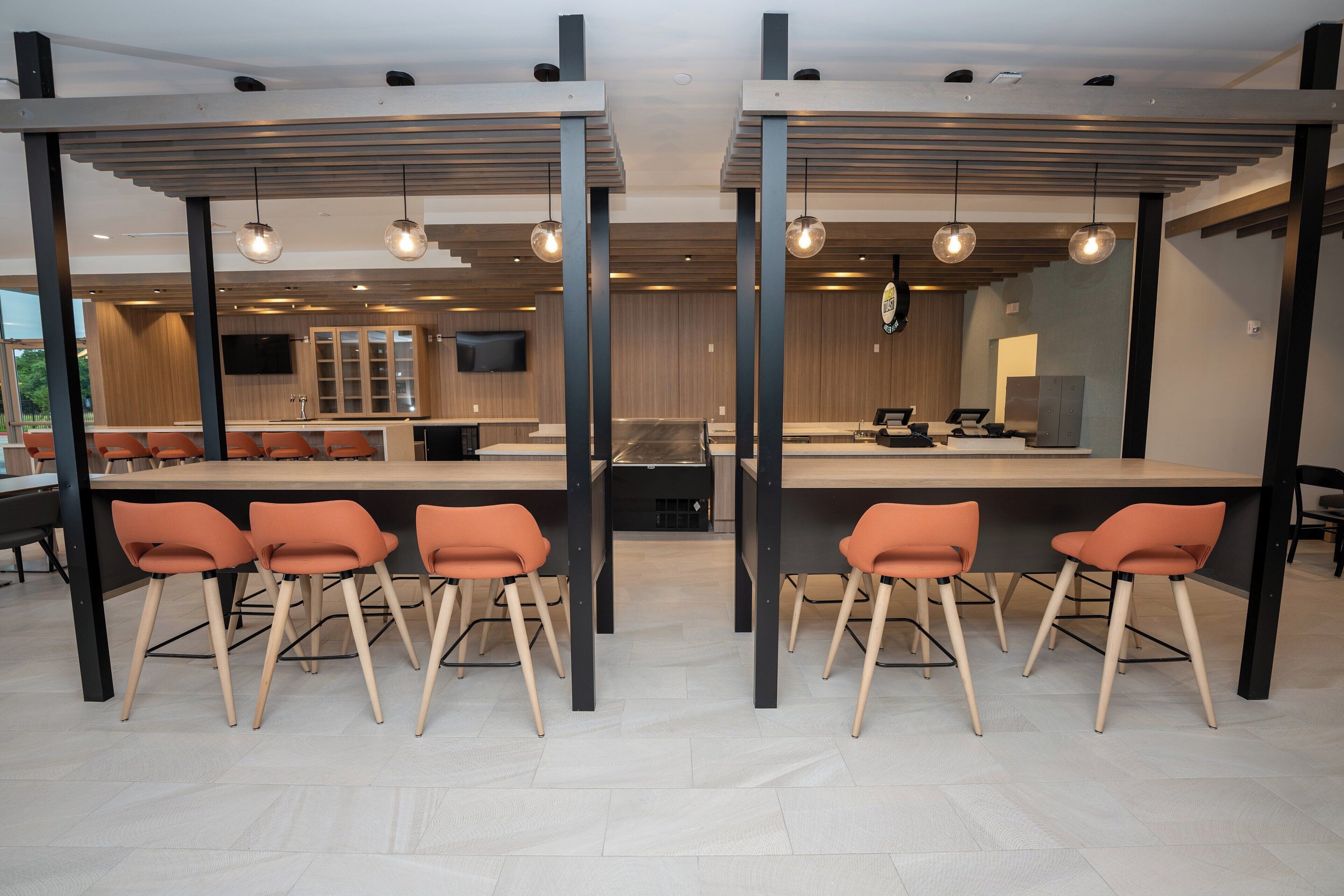 Un interior moderno con una barra central, asientos y una cocina al fondo.