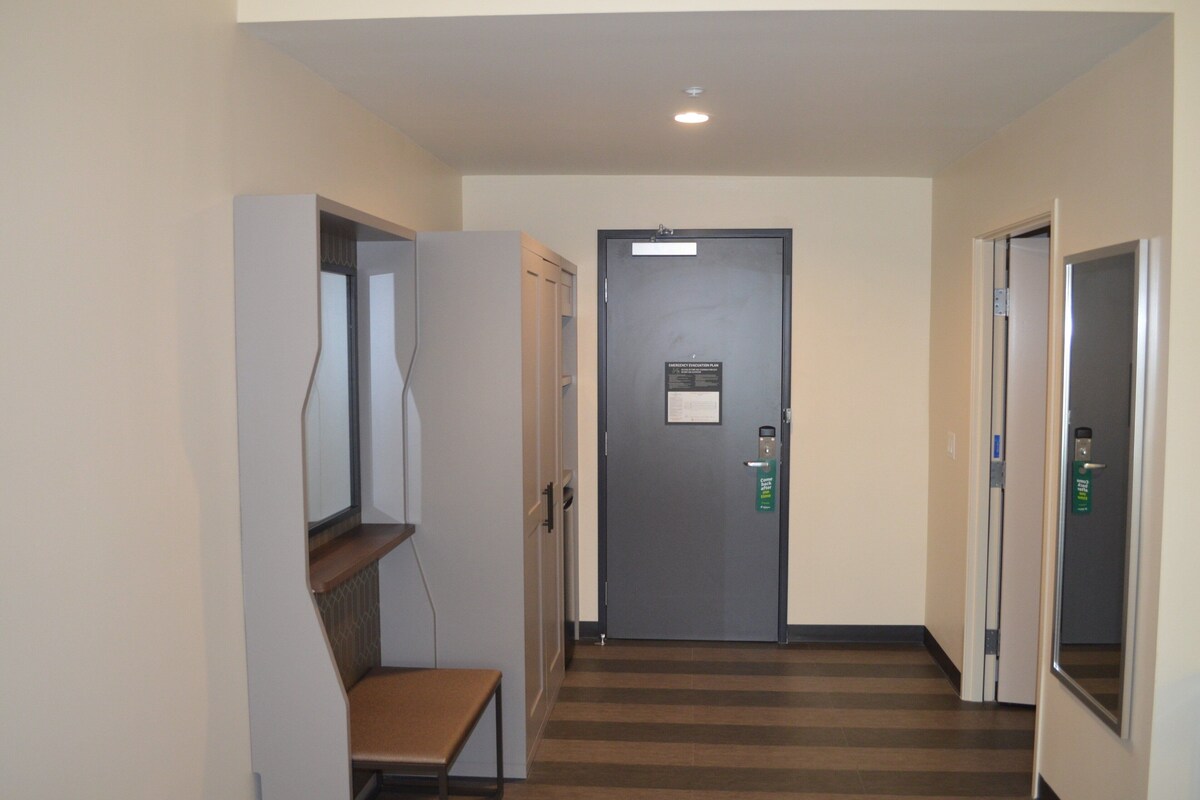 A hallway with a door, a bench, and a wall-mounted shelf.