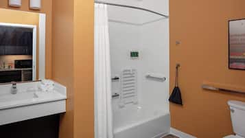 A bathroom with a white bathtub, a toilet, and a sink with a mirror.