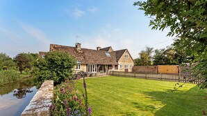 A traditional house with a stone facade, a grassy lawn, and a wooden fence.