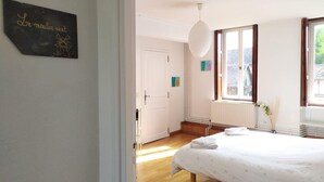 Een slaapkamer met een bed, een witte deur, een raam en een bordje dat aan de muur hangt.