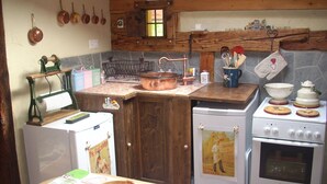 Una cocina con armarios de madera, una olla de cobre, una estufa Bosch y utensilios de cocina antiguos.