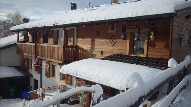 Un chalet de madera con balcón y techo cubierto de nieve.