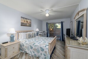 A bedroom with a bed, nightstands, a dresser, a ceiling fan, a TV, and a window with curtains. - Hip Nautic - Couple's Getaway, Indoor Pool Hot Tub, Walk to Beach, Pickleball (Hilton Head Island)