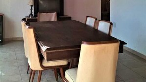 Un coin repas avec une table et des chaises en bois, un ventilateur de plafond et un téléviseur.