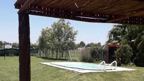 Un espace extérieur abrité, doté d’une piscine, et entouré de pelouse et d’arbres.