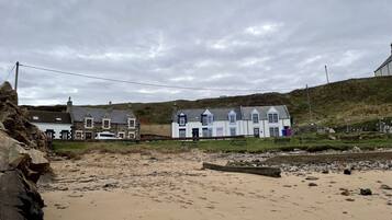 A coastal building with a stone facade, a white and blue color scheme, and a grassy area in front.