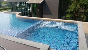Ein Schwimmbecken mit Fliesenrand und einer Holzterrasse.