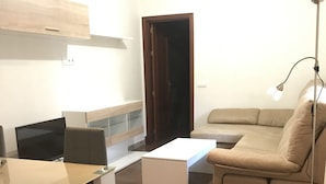 A modern living room with a sofa, a dining table, and a TV. - Mariñiguez Apartment. (Jerez de la Frontera)