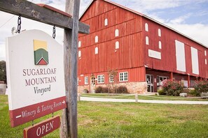 A sign for Sugarloaf Mountain Vineyard with a red barn in the background. - The Log House at Sugarloaf Mountain MD (Dickerson)