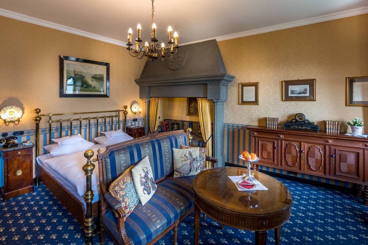 A hotel room with a large bed, a sofa, a round table, and a cabinet.