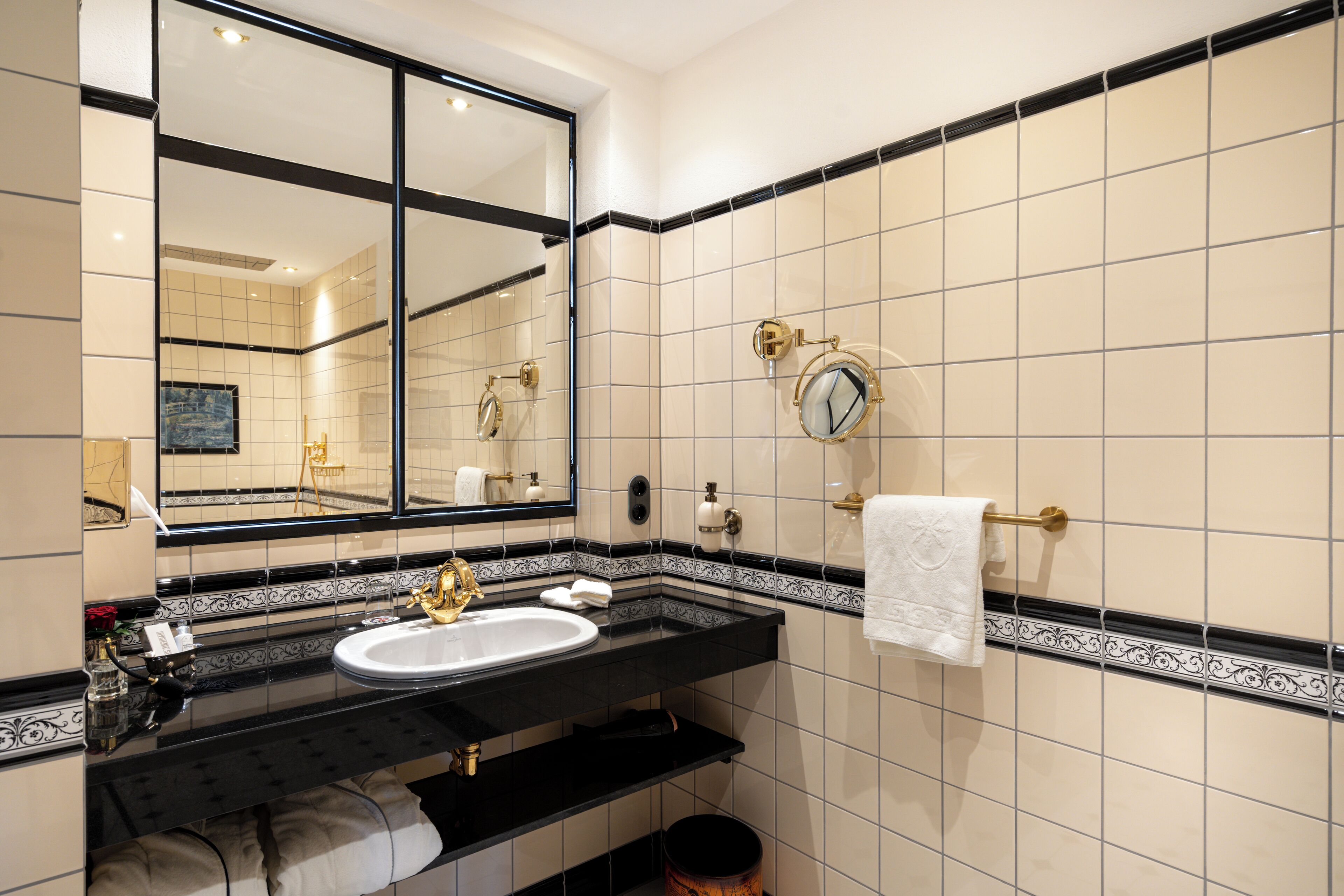 Un baño con lavamanos de encimera negro, un espejo grande y un perchero para toallas.