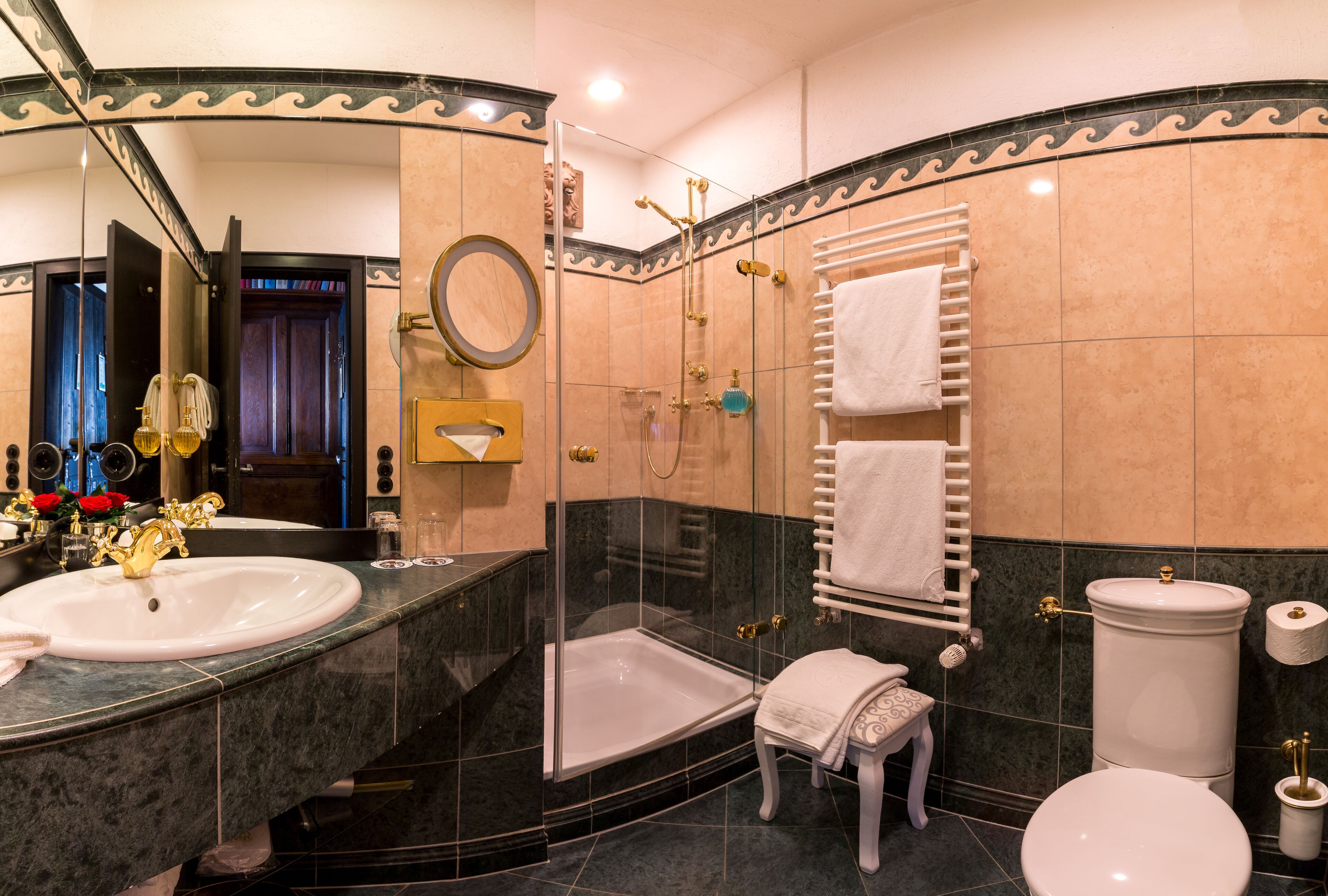 Un baño con un lavamanos grande, un inodoro, ducha con mampara de vidrio y un perchero para toallas.