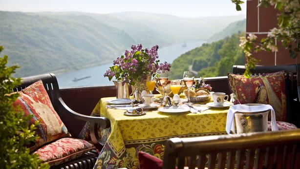 Mesa lista para el desayuno con vistas a un lago y montañas.