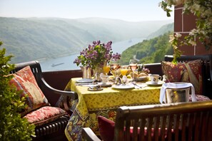 A dining table set with breakfast items and a view of a lake and mountains. - Burghotel Auf Schönburg (Oberwesel)