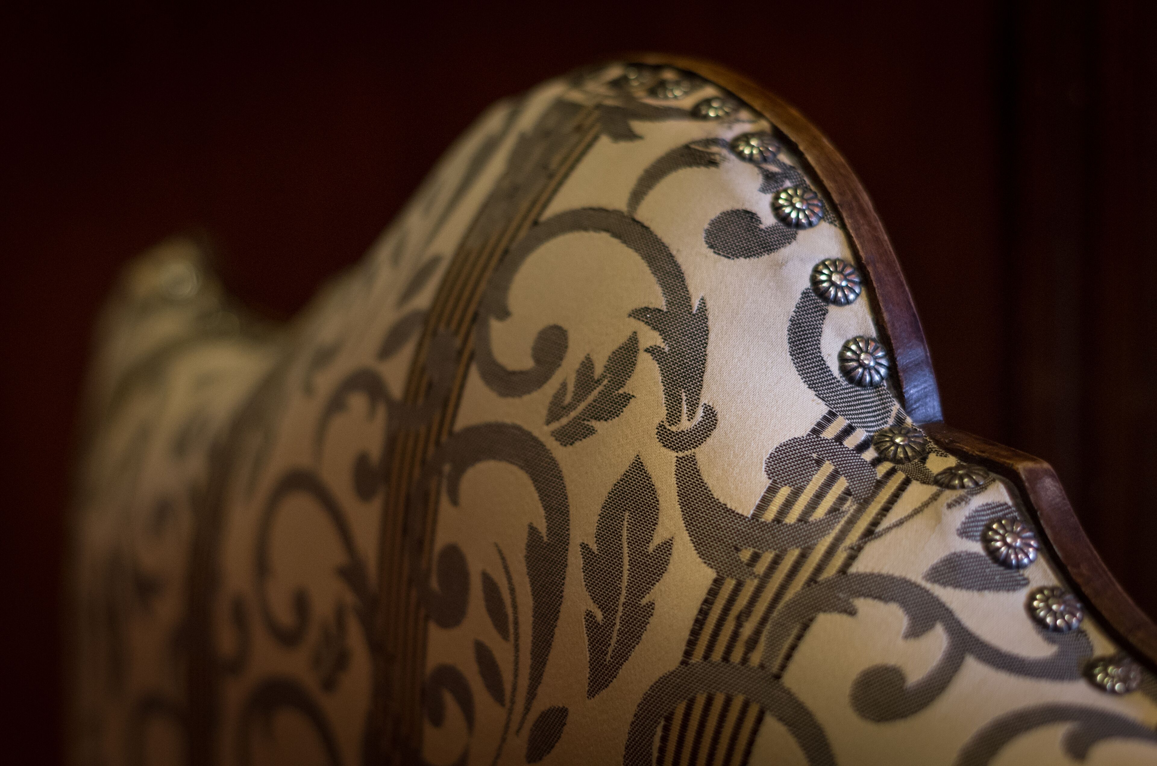 A close-up of a chair with ornate patterns and metallic embellishments.