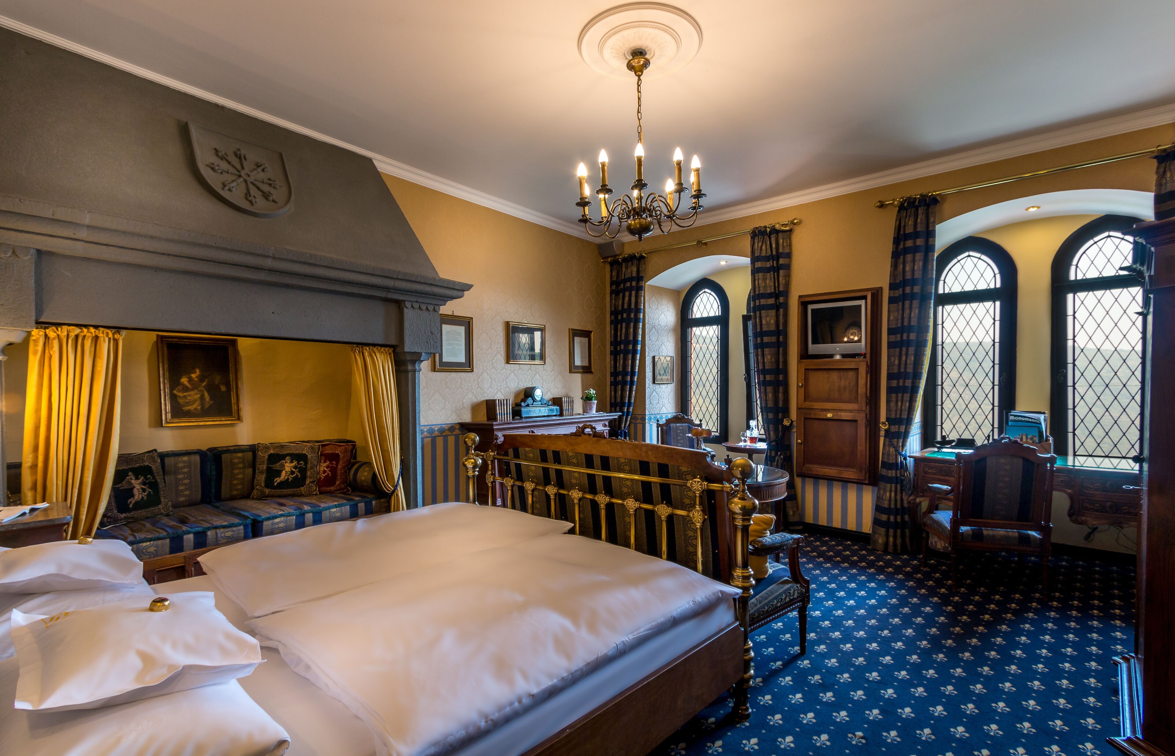 Ein traditionell eingerichteter Raum mit einem großen Bett, einem Schreibtisch und Blick durch Bogenfenster nach draußen.